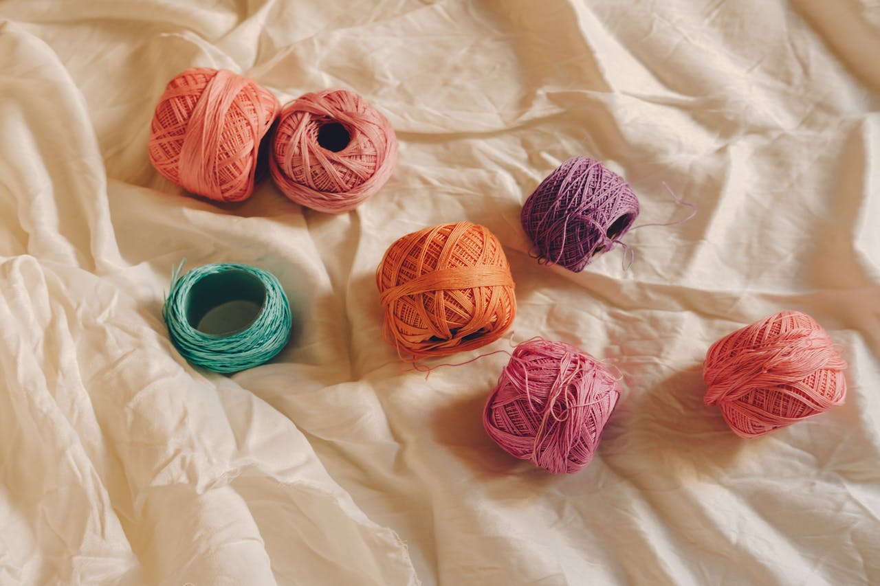 Top view of colorful yarn balls arranged on a soft beige fabric, perfect for crafting projects.
