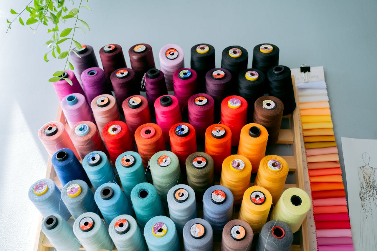 A vibrant collection of sewing threads displayed alongside fabric swatches in a creative studio.