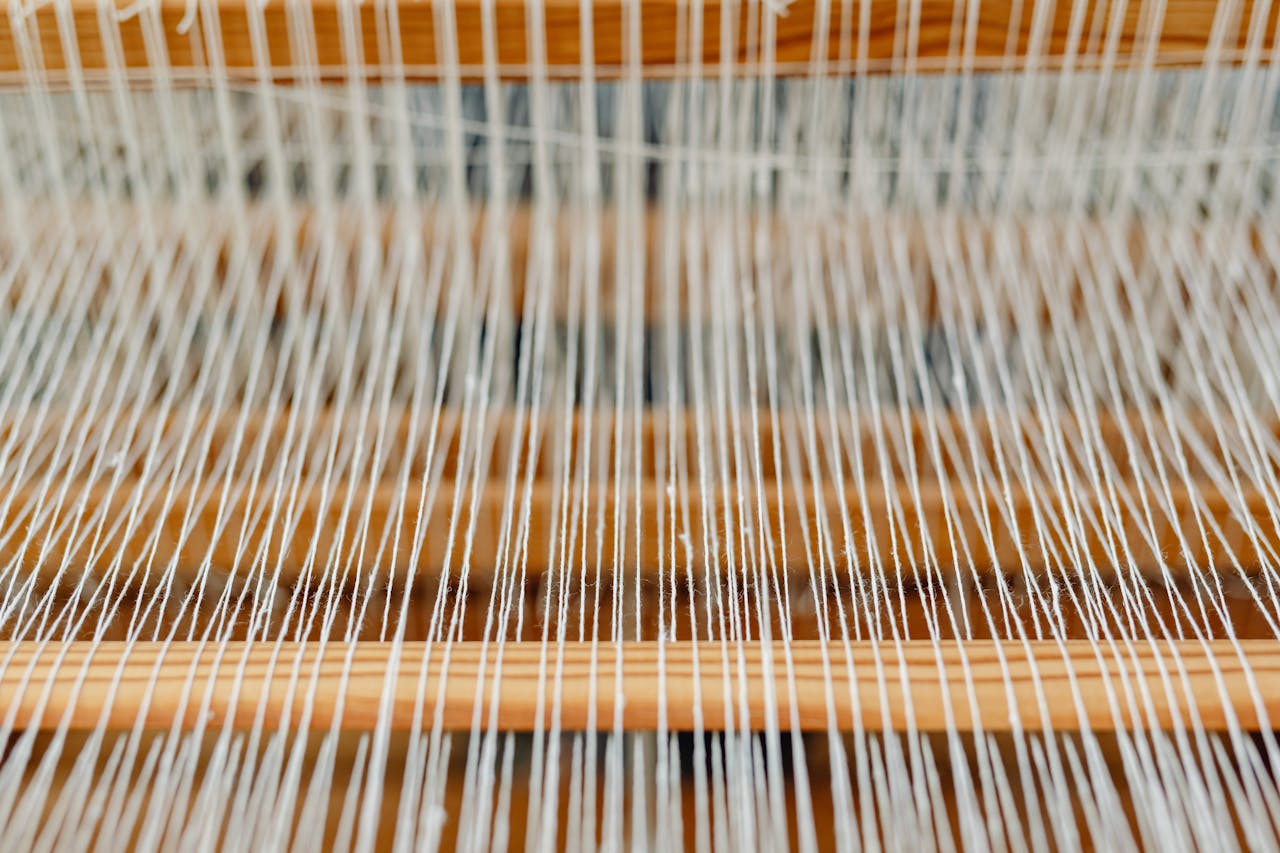Detailed view of a traditional wooden loom with fine yarn threads neatly arranged.
